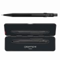 Matowy czarny ołówek automatyczny Caran d’Ache 844 Black Code obok otwartego czarnego metalowego etui Slimpack.