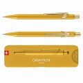 Złoty ołówek automatyczny Caran d’Ache 844 Goldbar obok dopasowanego złotego etui Slimpack.