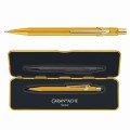 Złoty ołówek automatyczny Caran d’Ache 844 Goldbar obok dopasowanego złotego etui Slimpack.