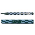 Długopis Caran d’Ache 849 Mosaic Spruce Green w kolorze ciemnej zieleni z niebiesko-szarym wzorem mozaiki ułożony nad pasującym etui.
