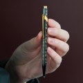 Prezentacja długopisu Caran d’Ache 849 Horse trzymanego w dłoni podkreślająca ergonomiczny sześciokątny kształt.