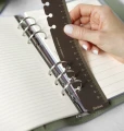 Dlon-wkladajaca-brazowa-plastikowa-linijke-z-podzialka-i-logo-Filofax-w-srebrne-ringi-mechanizmu-organizera