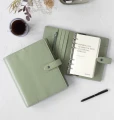 Dwa-zielone-organizery-Filofax-Malden-Vetiver-na-jasnym-blacie-obok-filizanki-kawy-i-czarnego-piora