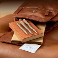 Zdjęcie lifestylowe przedstawiające zestaw trzech instrumentów Parker IM Sandstone PVD leżących na książce obok skórzanej torby