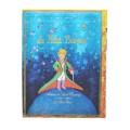Tylna okladka notesu Paperblanks Maly Ksiaze z ilustracja bohatera patrzacego na gwiazdy i francuskim tekstem rekopisu Antoine de Saint-Exupery.