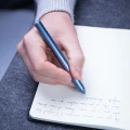 Zbliżenie na czubek niebieskiego długopisu Novium Hoverpen Classic Midnight Blue piszącego w notesie