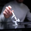 Mężczyzna sięgający po srebrne pióro Novium Hoverpen Future Deep Silver lewitujące na ciemnym, eleganckim biurku