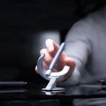 Mężczyzna sięgający po niebieskie pióro Novium Hoverpen Future Deep Blue lewitujące w podstawie na biurku